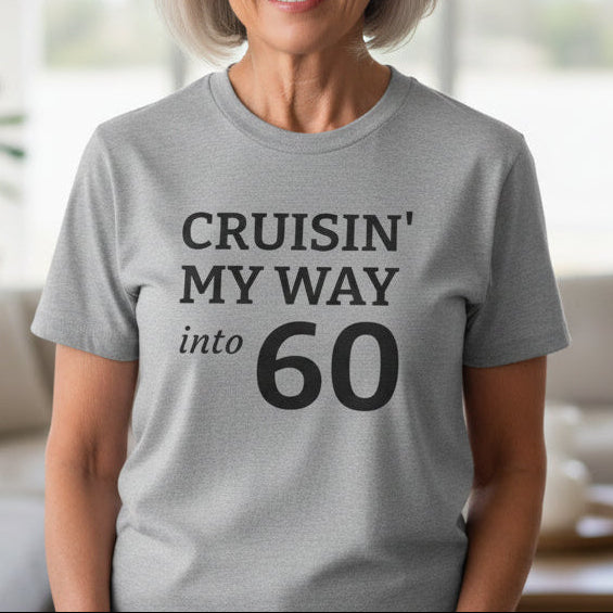 Woman wearing a gray t-shirt with 'CRUISIN' MY WAY into 60' text in a living room.