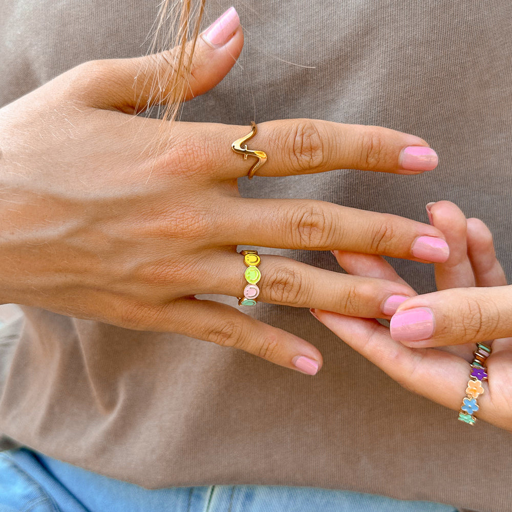 Close-up of hands wearing colorful rings with a neutral background