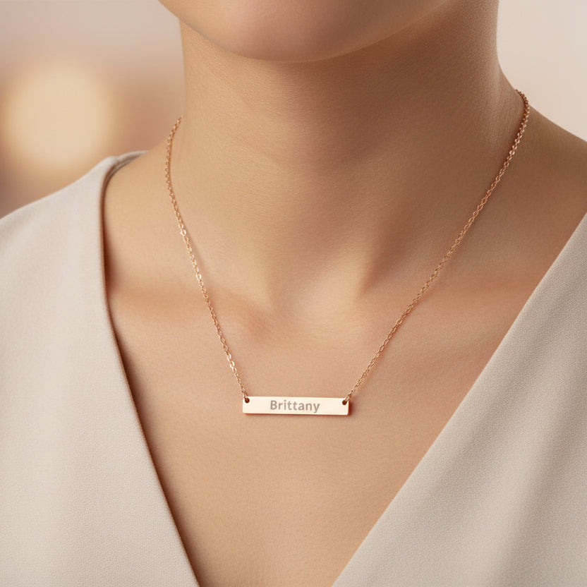 Rose gold necklace with a bar pendant engraved with 'Brittany' on a white background