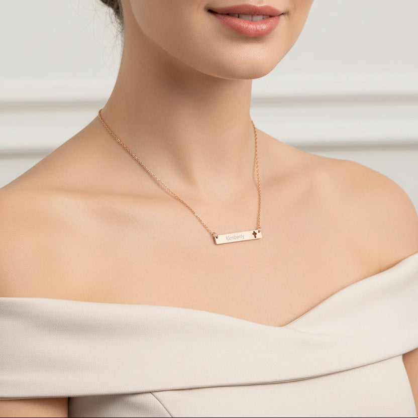 Rose gold necklace with a bar pendant engraved with 'Kimberly' and a cut-out cross on a white background.