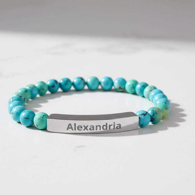 Turquoise beaded bracelet with a silver name tag on a white background
