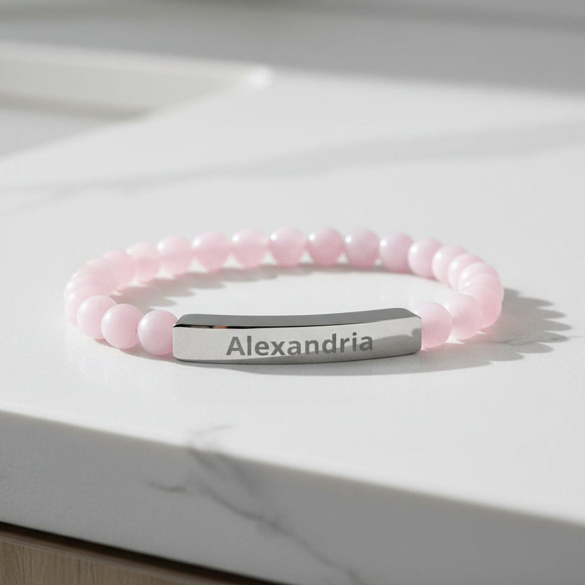 Pink beaded bracelet with a silver bar on a marble surface
