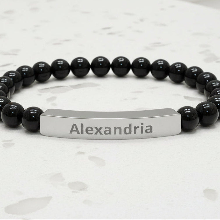 Black beaded bracelet with a silver name tag on a white background