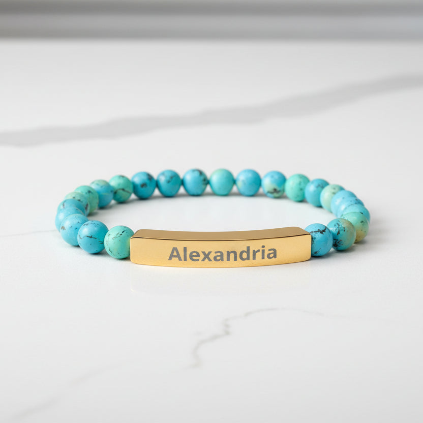 Turquoise beaded bracelet with a gold tag displaying 'Alexandria' on a white background