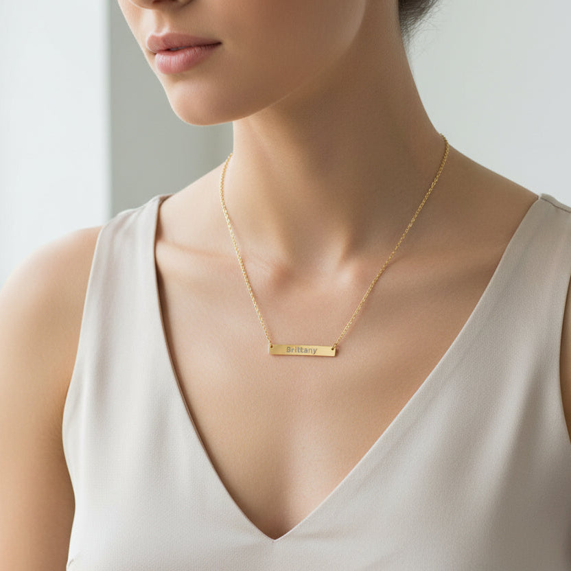Gold necklace with a bar pendant engraved with 'Brittany' on a white background