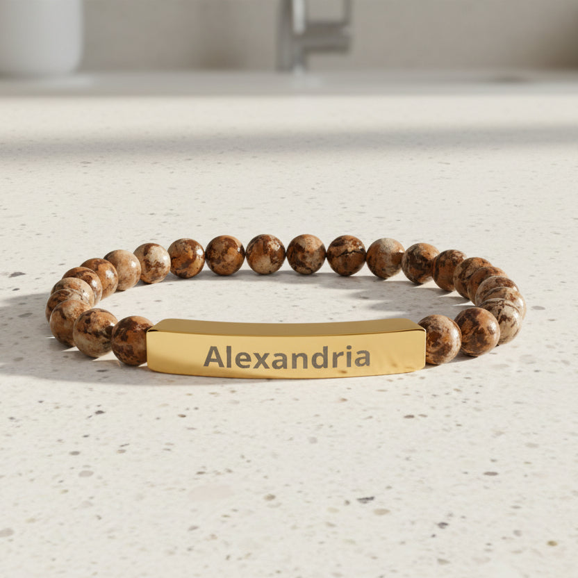 Bracelet with brown beads and gold tag displaying 'Alexandria' on a white background