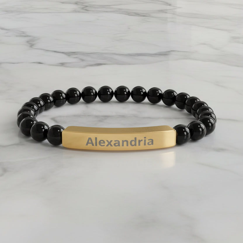 Black beaded bracelet with a gold name tag on a white background