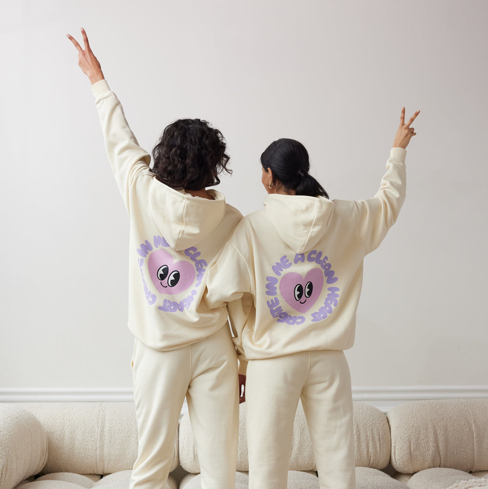 Two people wearing matching cream-colored outfits with a purple flower design on the back, standing in a room.