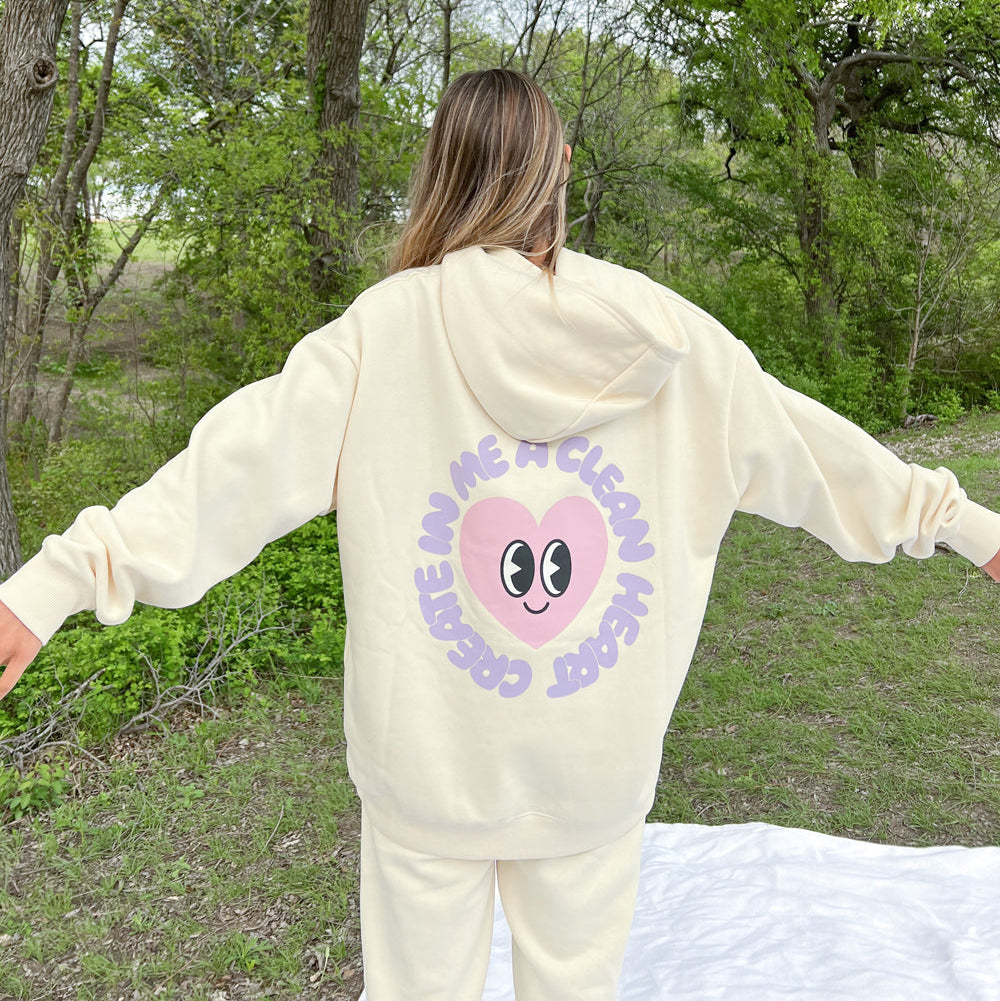 Person wearing a cream-colored hoodie with a graphic design outdoors