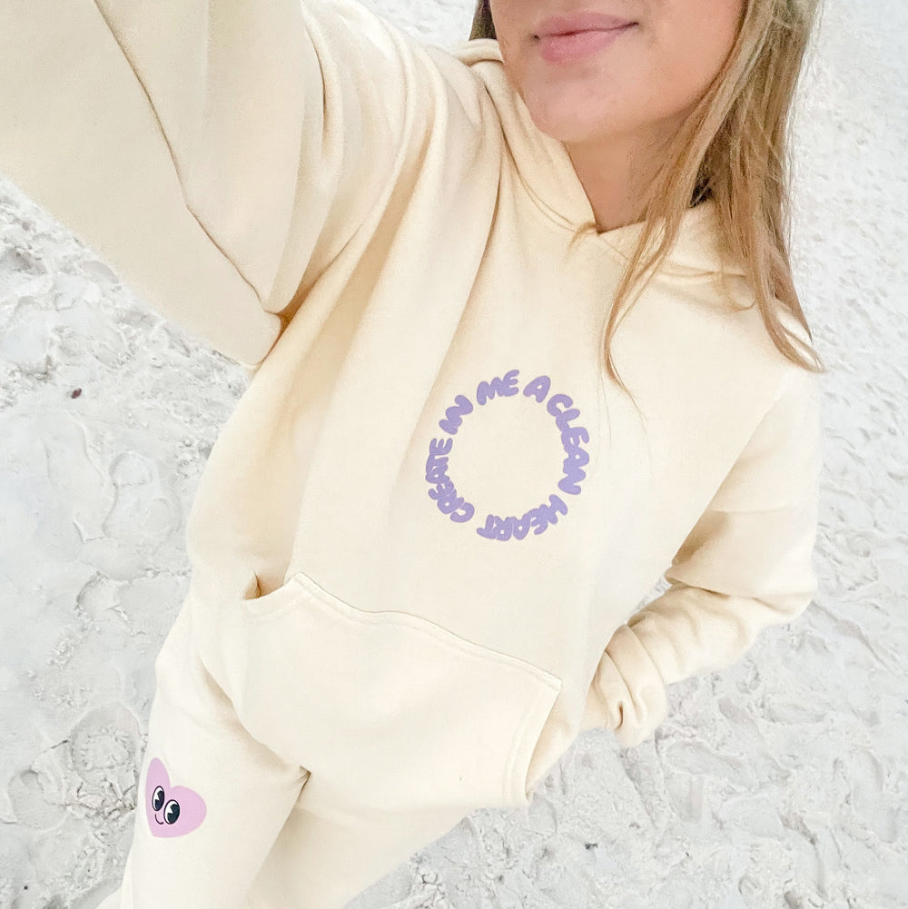 Person wearing a light-colored hoodie with text and graphics on a textured surface