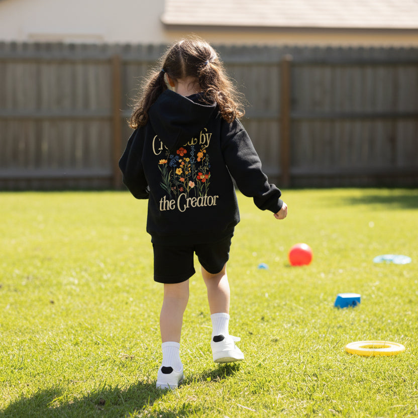 Child wearing a black hoodie with floral design and text on a white background