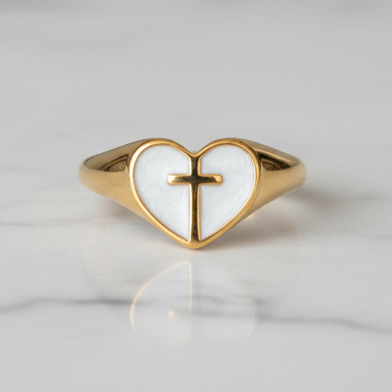 Gold ring with a heart-shaped design and cross on a white background