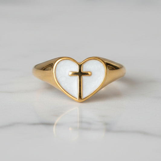 Gold ring with a heart-shaped design and cross on a white background