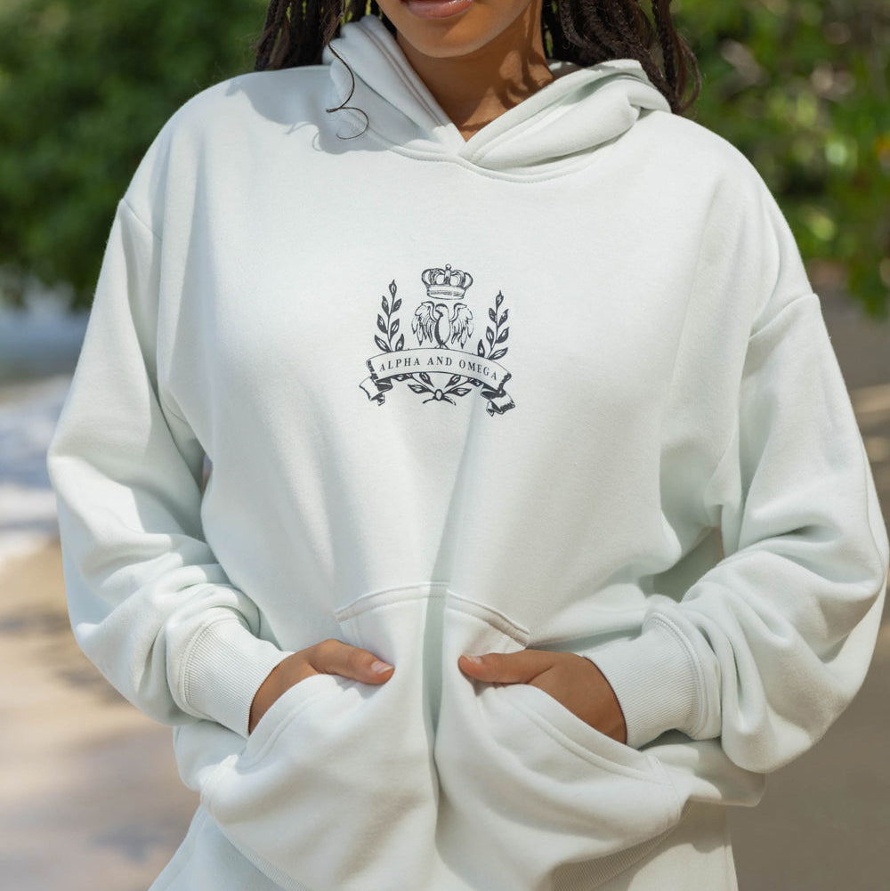 Person wearing a white hoodie with a logo outdoors
