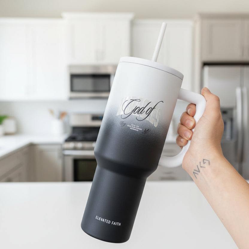 Person holding a black and white travel mug with text on a white background