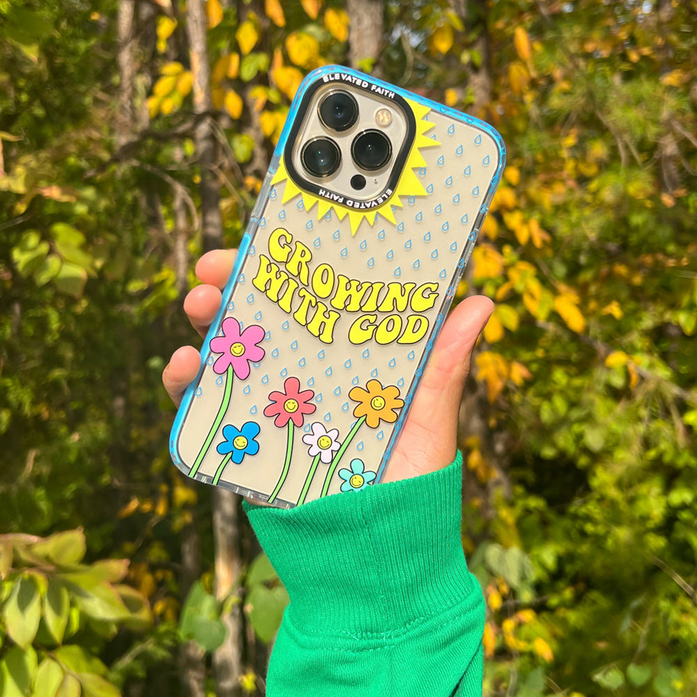 Phone case with 'Growing with God' text held in front of a forest background