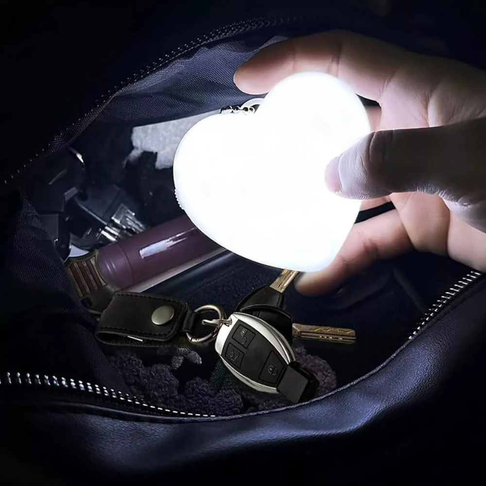 Hand holding a small light bulb over an open bag with keys and other items.
