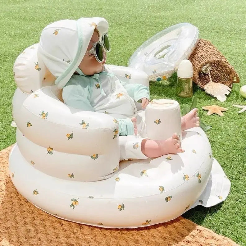 Baby sitting in a inflatable seat with a green grass background