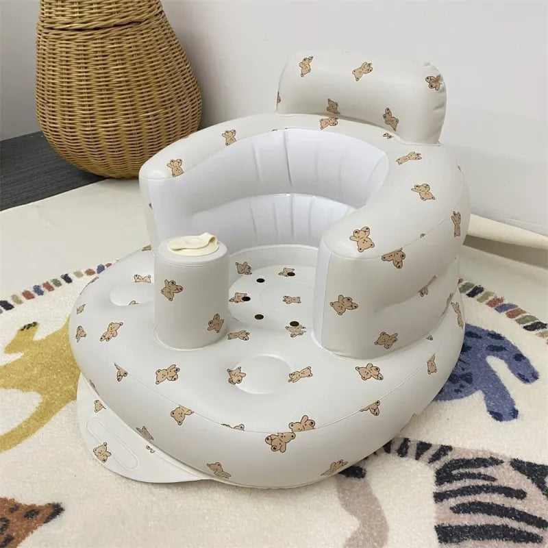 White baby seat with teddy bear pattern on a colorful rug