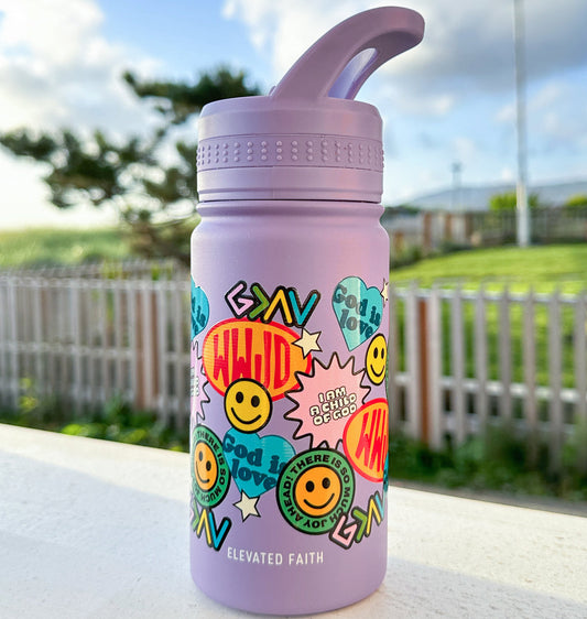 Pink water bottle with colorful designs and text on a white surface with a blurred outdoor background