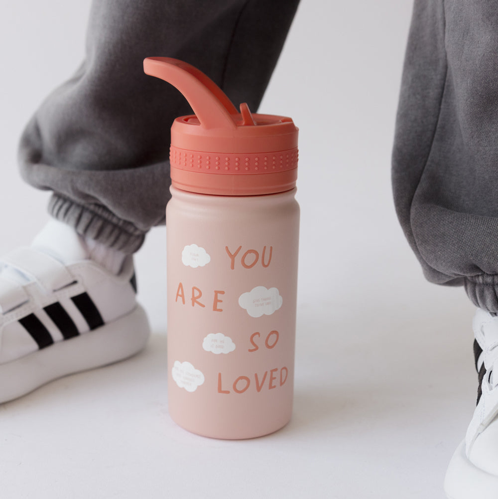 Pink water bottle with 'You are so loved' text and cloud designs, worn by a person in gray pants and white sneakers.
