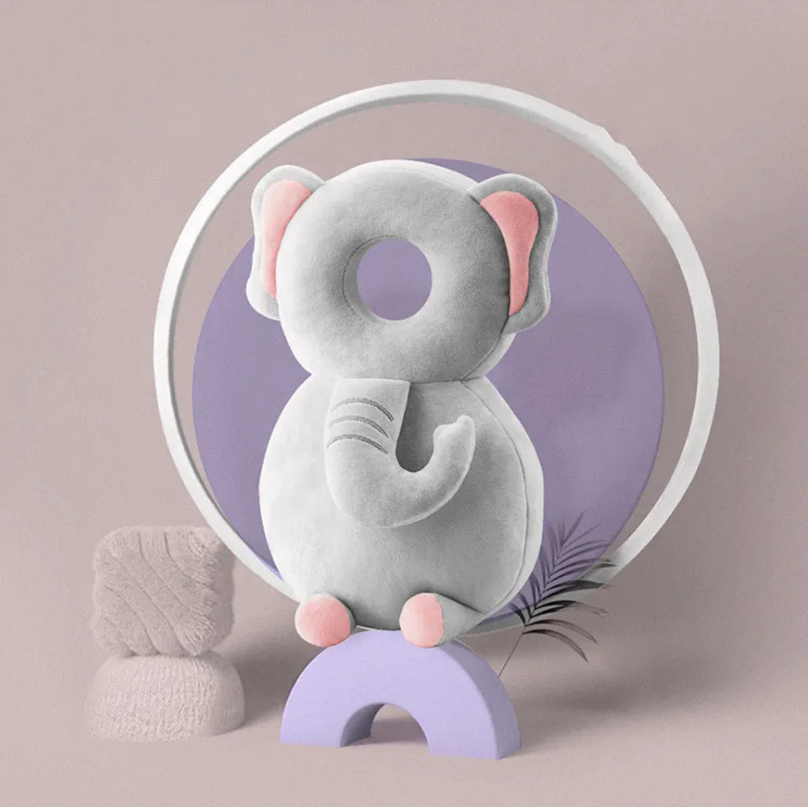 Gray elephant plush toy with pink accents on a purple stand against a beige background