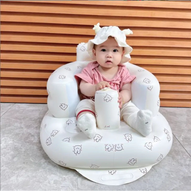 Baby sitting in a white inflatable chair with animal patterns against a wooden background